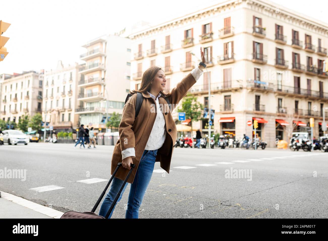 Giovane donna in città che ha salutato un taxi, Barcellona, Spagna Foto Stock