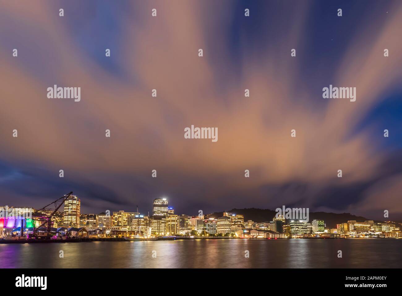 Nuova Zelanda, Wellington, nuvole sullo skyline illuminato della città sul lungomare di notte Foto Stock