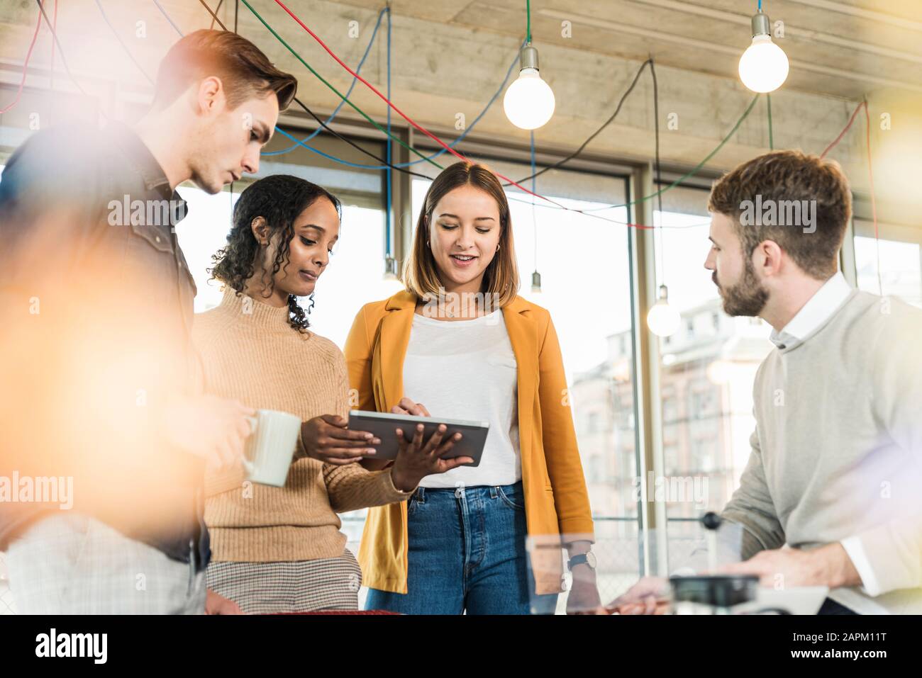 Giovani aziende che hanno una riunione in ufficio che condivide un tablet Foto Stock