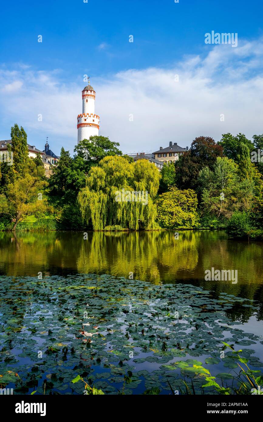 Germania, Assia, Bad Homburg vor der Hohe, Torre Bianca che sorge sopra gli alberi che circondano il lago verde Foto Stock