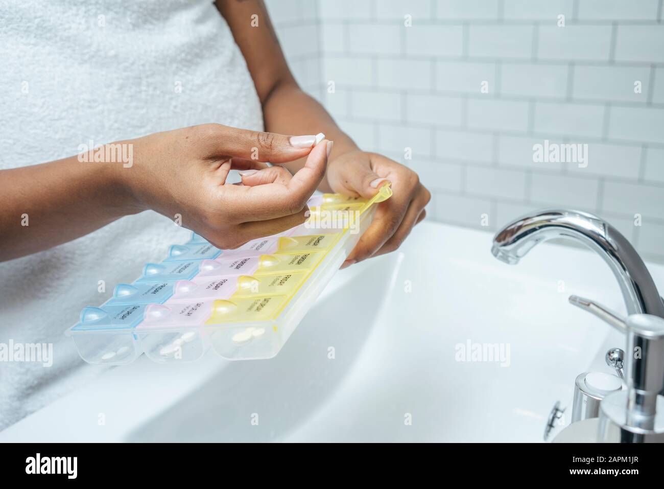 Primo piano di donna che prende la pillola in bagno Foto Stock