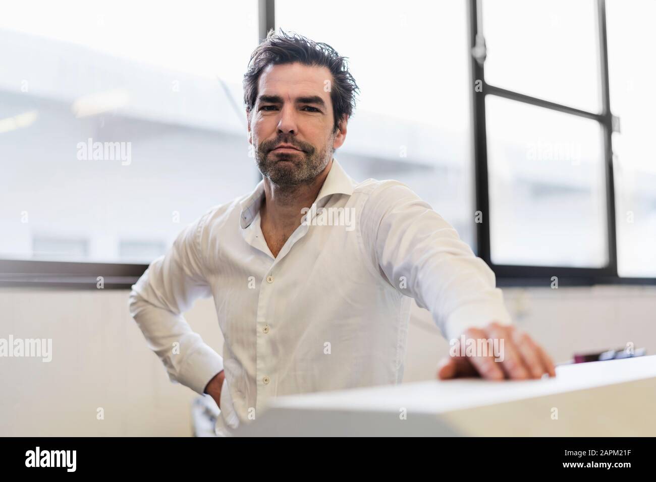Ritratto di un uomo d'affari sicuro alla finestra in una fabbrica Foto Stock