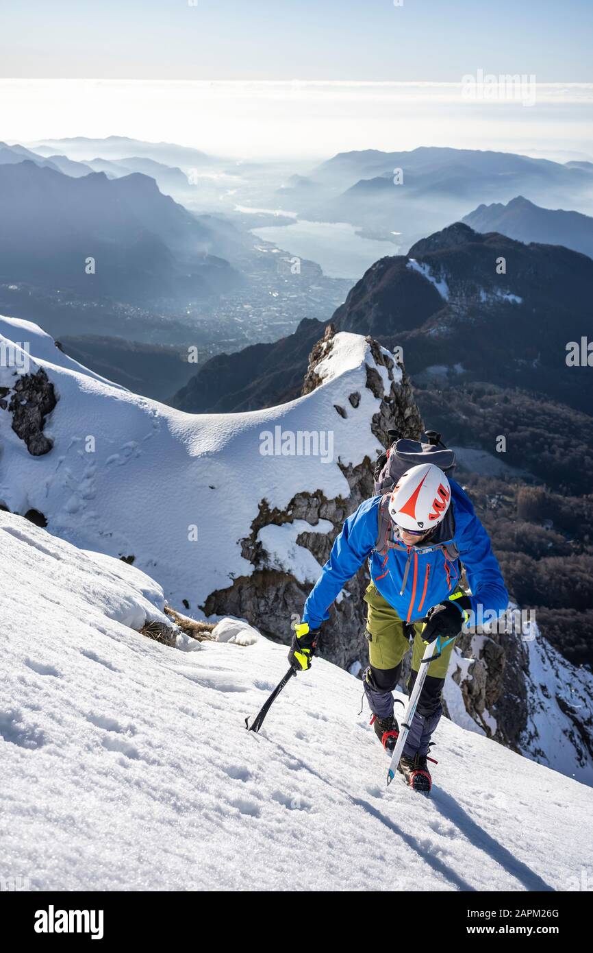 Alpinista che sale su una montagna innevata, Alpi Orobie, Lecco, Italia Foto Stock
