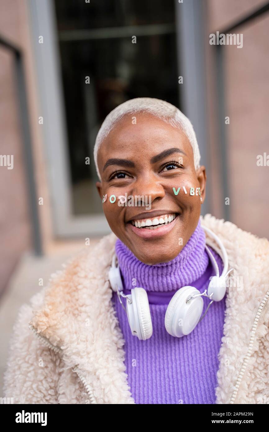 Ritratto di donna dai capelli bianchi matura con cuffie bianche e adesivi in faccia, buone vibrazioni Foto Stock