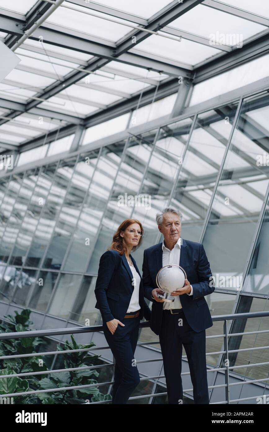 Uomo d'affari e donna d'affari che tiene il globo in moderno edificio dell'ufficio Foto Stock