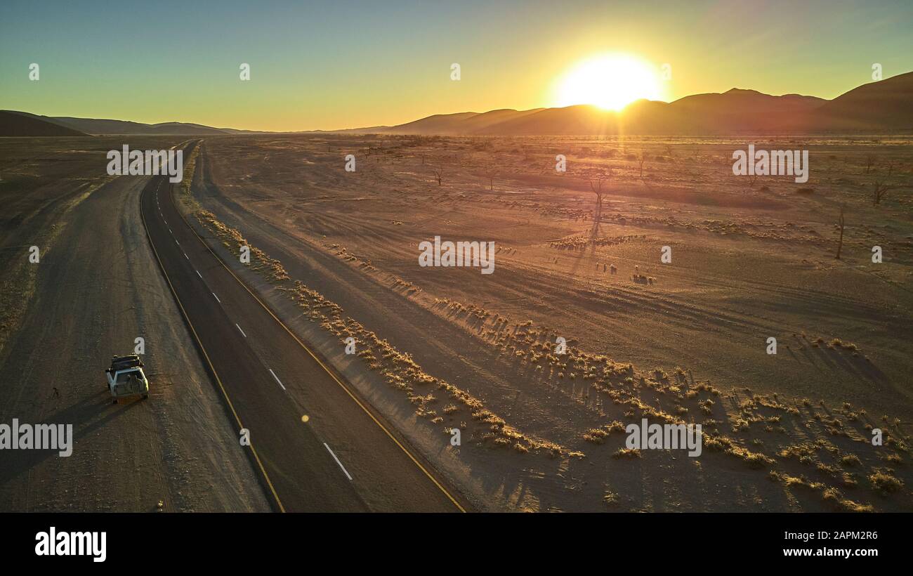 Jeep guida su una pista sporca nel deserto del Namib con sole nascosto dietro le dune, Namibia Foto Stock
