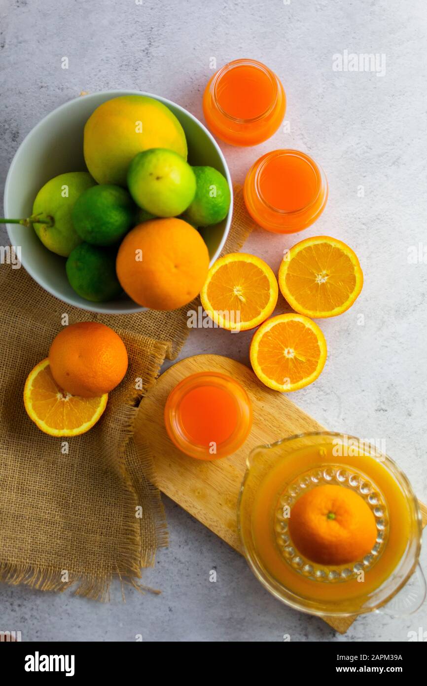 Spremiagrumi, agrumi maturi e vasetti di succo d'arancia appena spremuto Foto Stock
