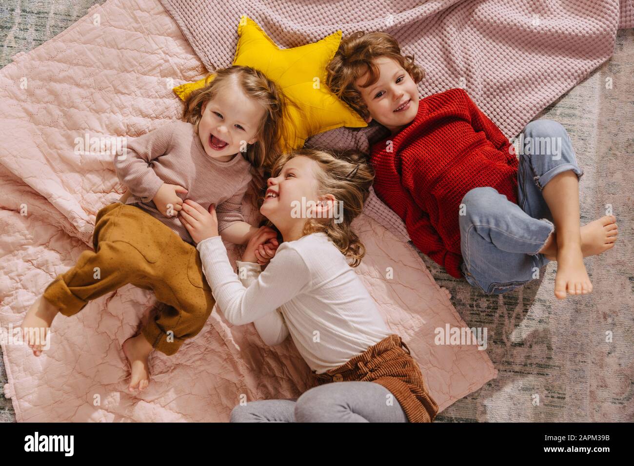 Tre ragazze felici sdraiate sulle coperte a casa Foto Stock