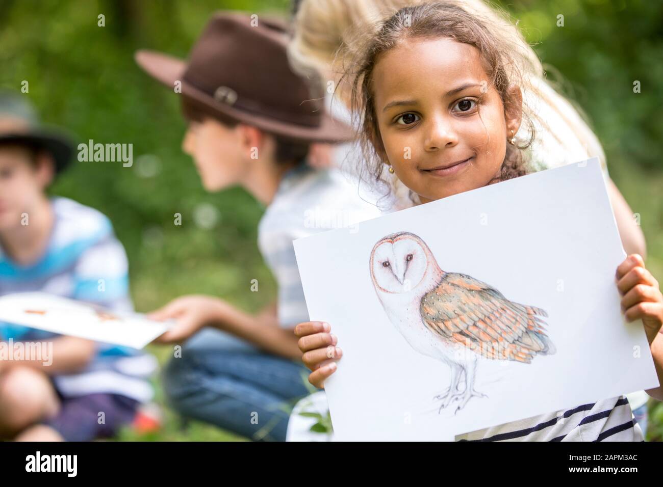 Bambini della scuola che imparano circa la specie animale, ragazza che tiene l'immagine di un uccello Foto Stock