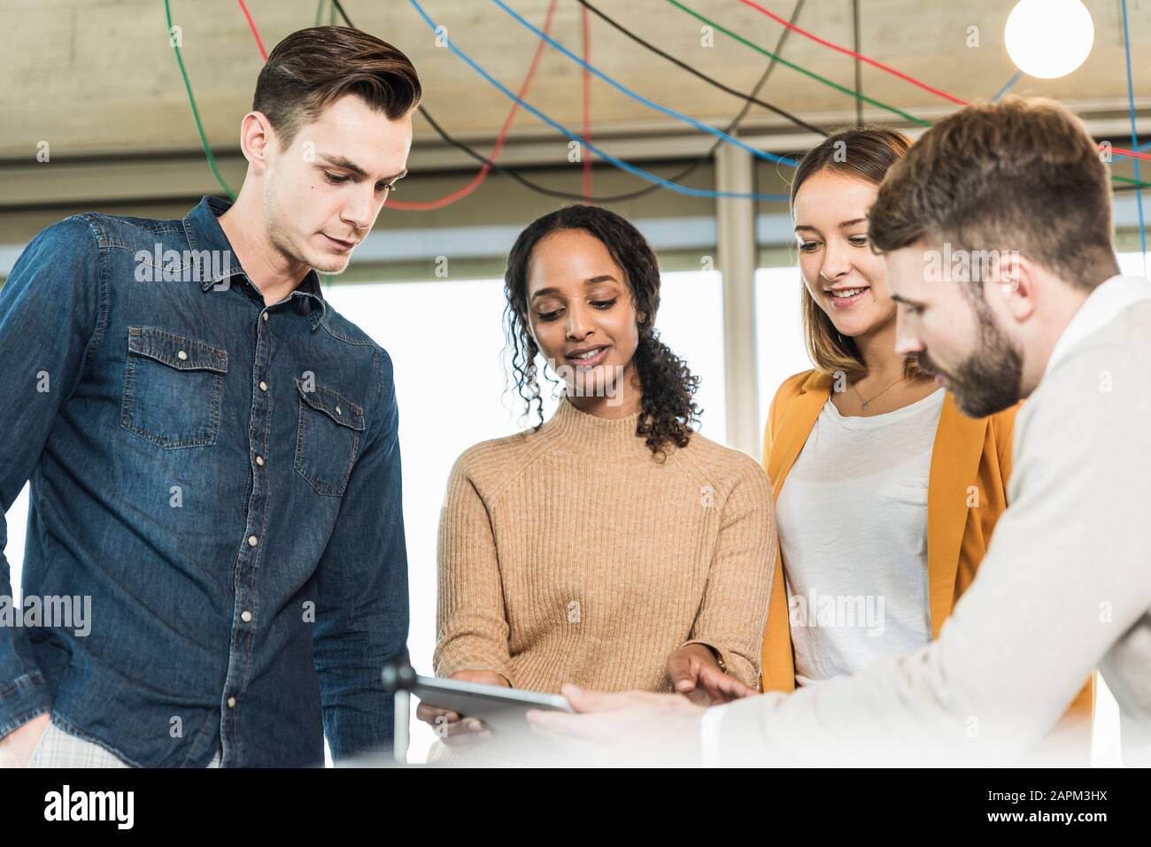 Giovani aziende che hanno una riunione in ufficio che condivide un tablet Foto Stock