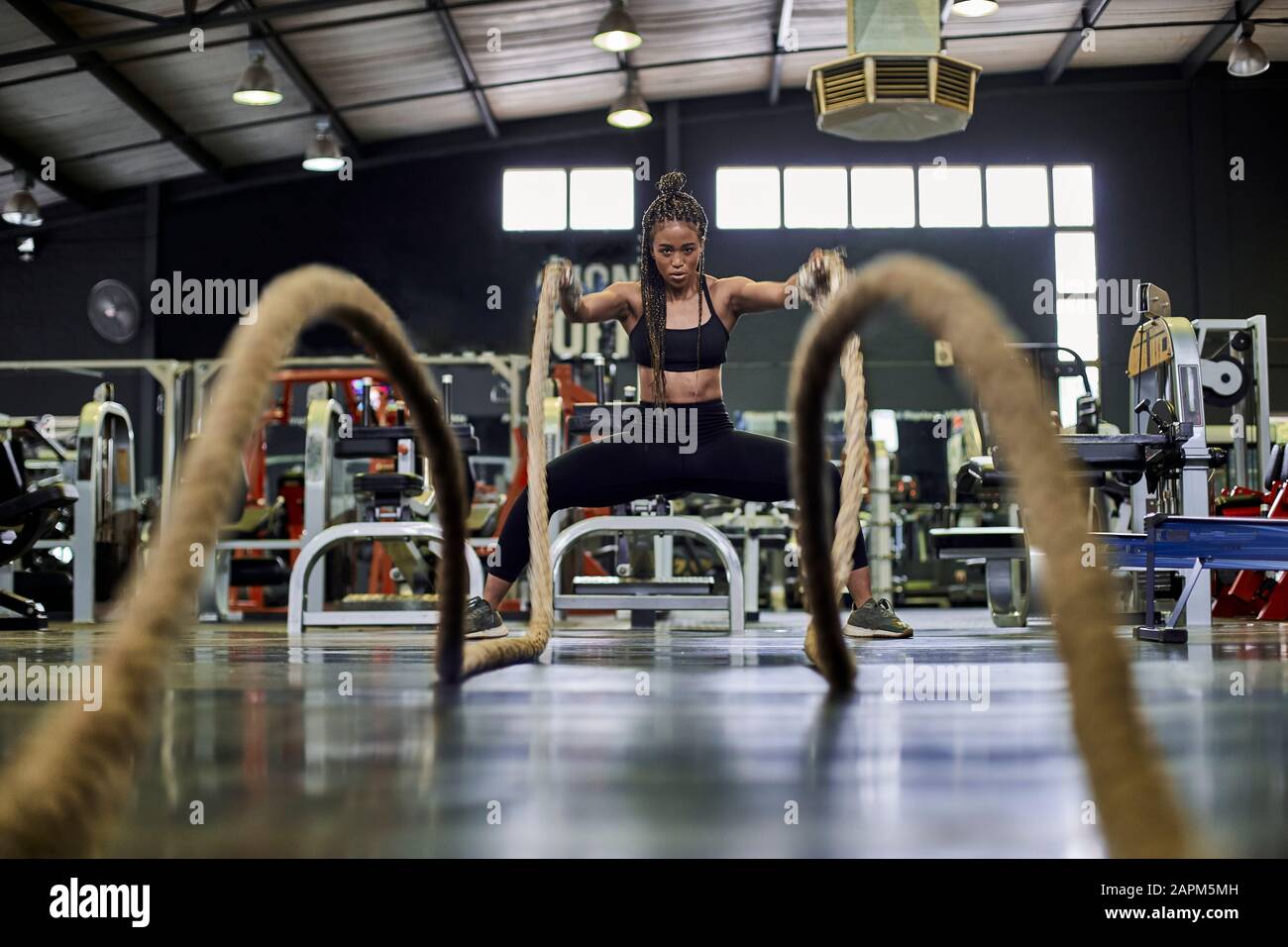 Atleta femminile che fa addestramento di resistenza con le corde pesanti in palestra Foto Stock