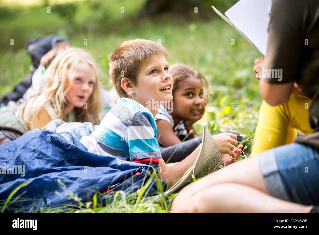 Insegnante di lettura storia per i bambini a scuola, campeggio nella foresta Foto Stock