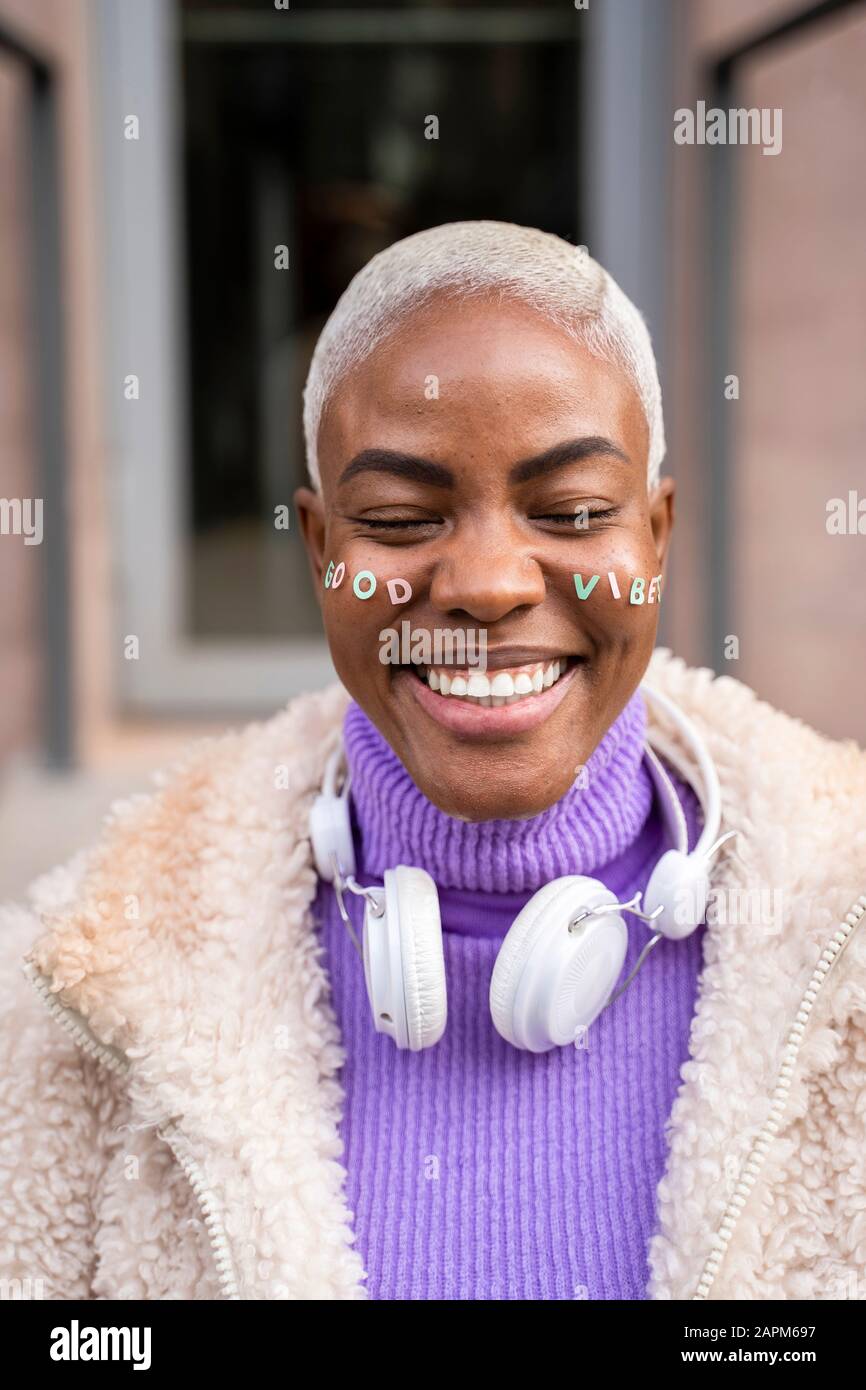 Ritratto di donna dai capelli bianchi matura con cuffie bianche e adesivi in faccia, buone vibrazioni Foto Stock