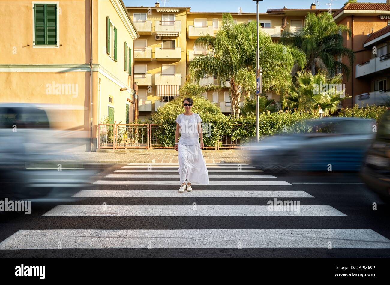 Donna sorridente che attraversa la strada sulla traversata zebra, Italia Foto Stock