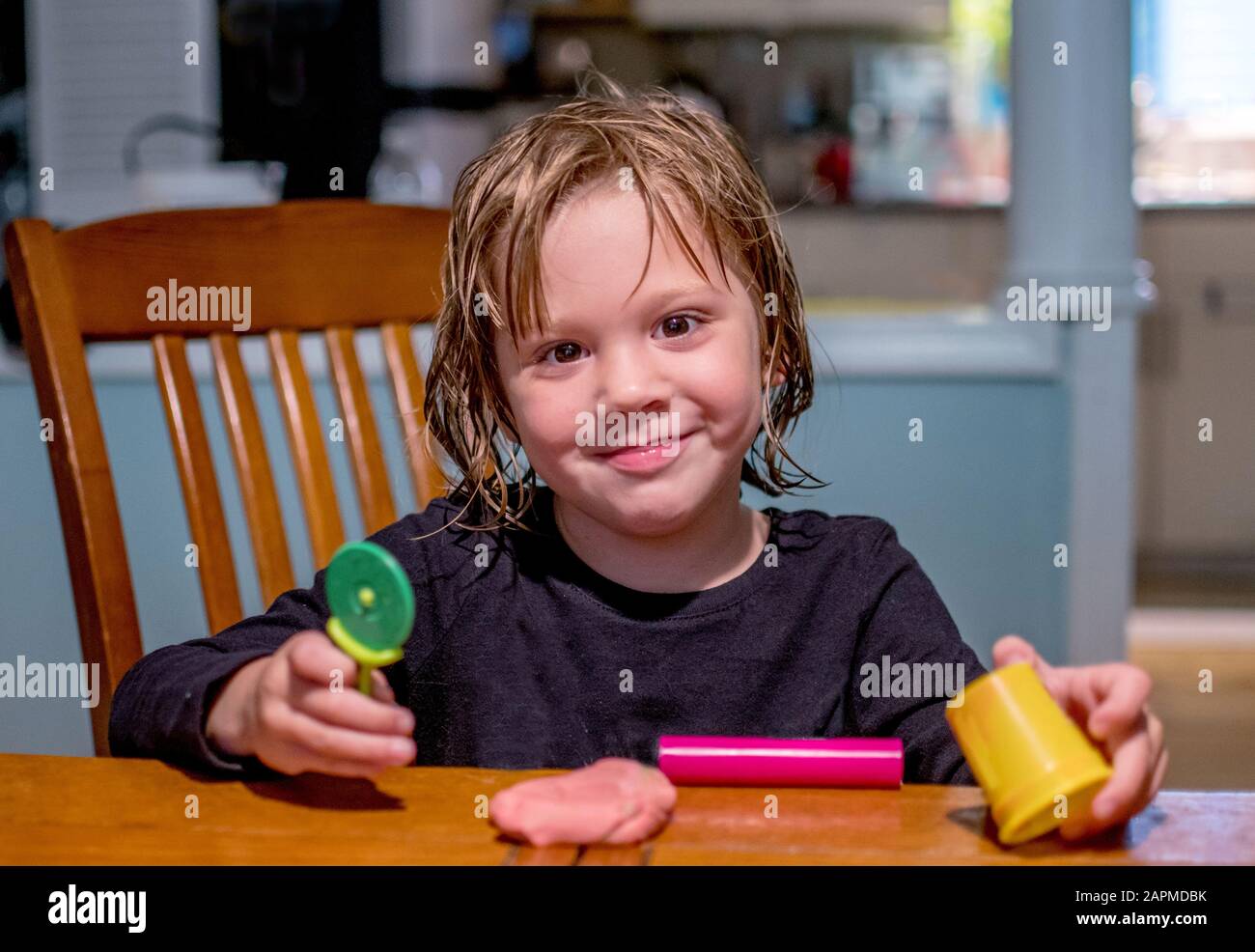 Orgogliosa bambina lampeggia un grin come mostra fuori la sua creazione di argilla gioco Foto Stock