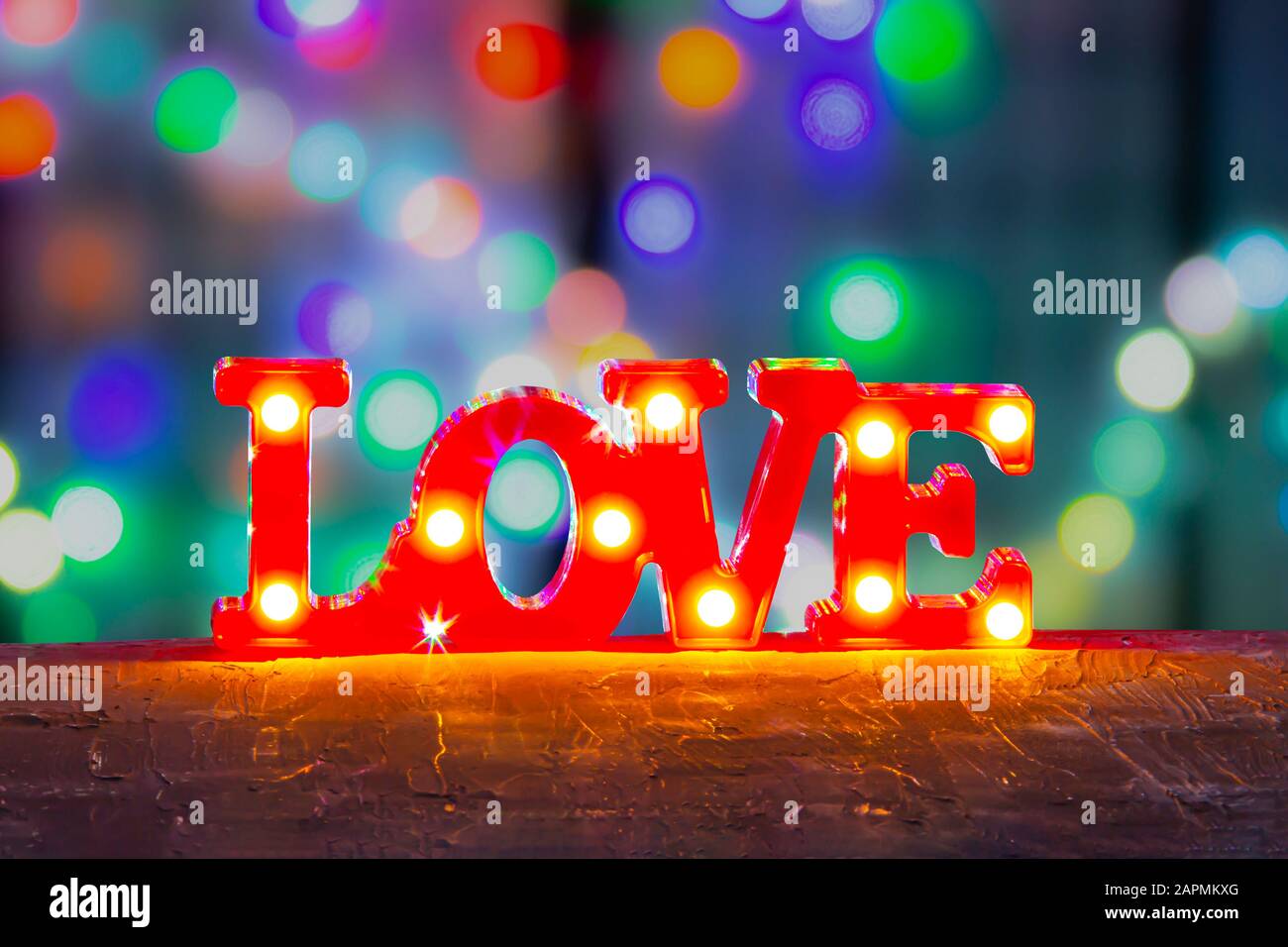 Love segno Camera Decor con luci LED Marquee Letters su rosso con colori vivaci defocused luci sfondo. Foto Stock
