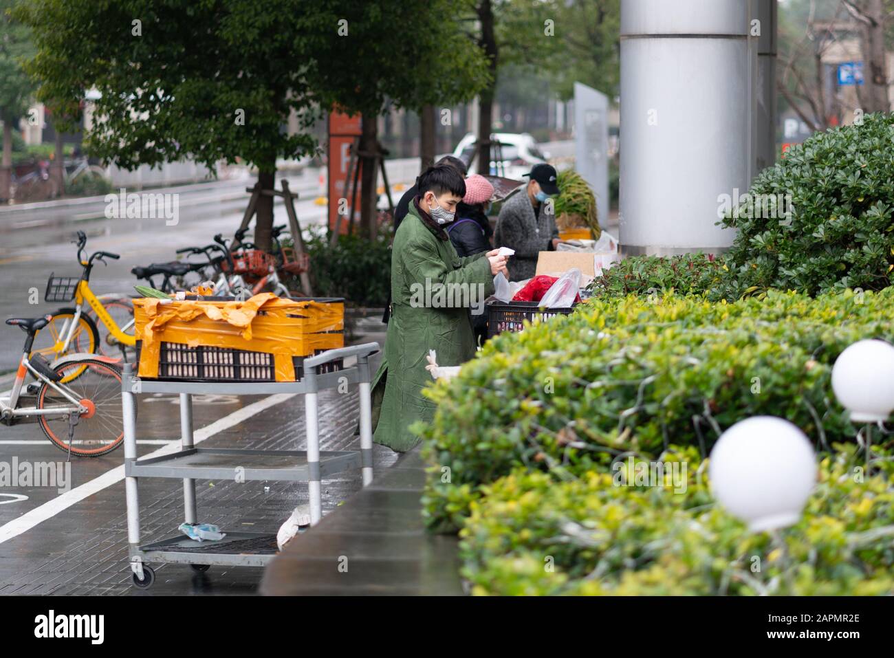 Wuhan China , 24 gennaio 2020 : Persone che indossano maschere che vendono cibo per strada durante il secondo giorno del blocco della città per prevenire il coronavirus e. Foto Stock