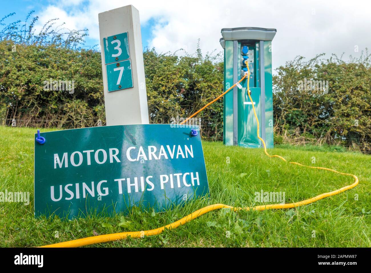 Caravan a motore con questo passo. Firmare un numero di piazzola del campeggio, con il cavo elettrico che corre da un palo di alimentazione sul retro. Inghilterra, Regno Unito. Foto Stock