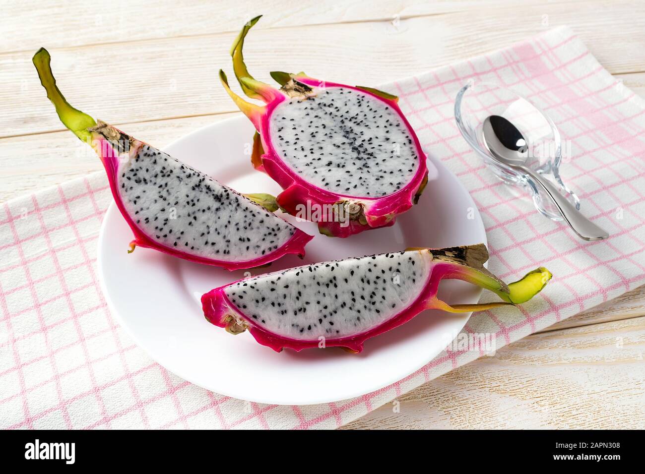 Tagliate tre parti di pitaya maturo o di frutti di drago su un piatto sopra un tavolo di legno bianco. Sano cibo vegetariano ricco di vitamine B e tannino. Foto Stock