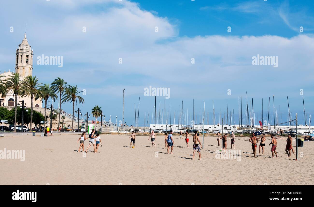 Sitges, SPAGNA - 27 LUGLIO 2018: Persone che giocano a pallavolo presso la spiaggia di Platja de la Fragata a Sitges, Spagna, evidenziando Sant Bartomeu i Santa te Foto Stock