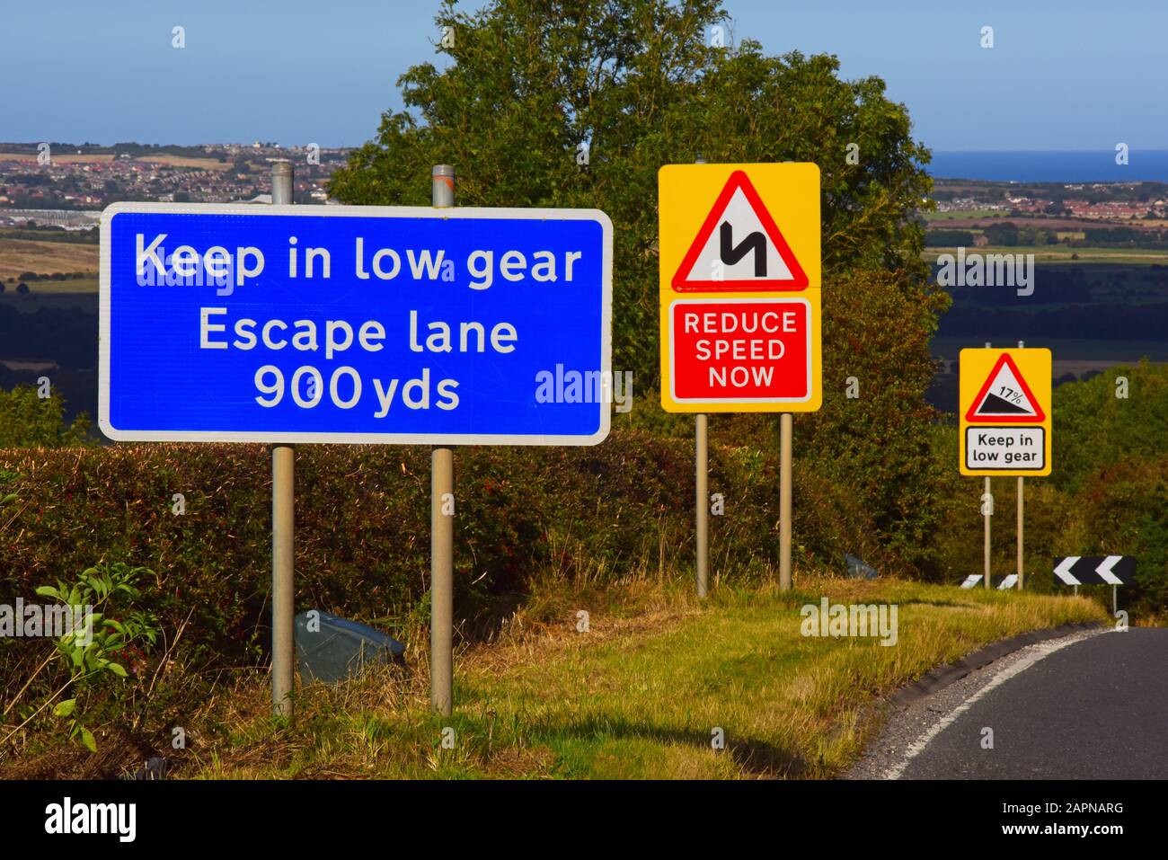 molti cartelli stradali in cima alla collina di faxton, avvertimento di discesa ripida, curve e corsia di fuga di emergenza davanti, yorkshire regno unito Foto Stock