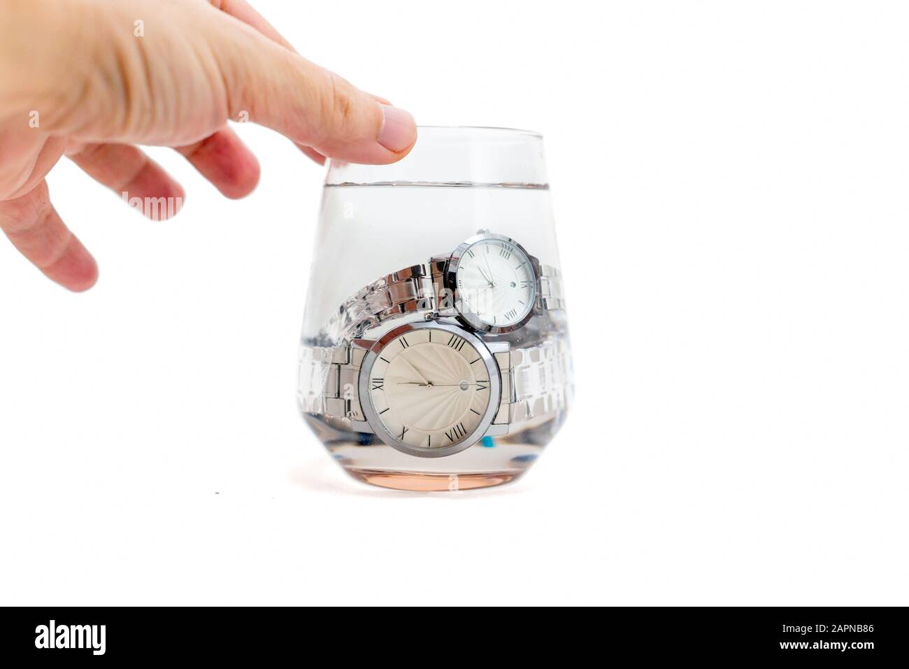 Mano uomo tenuta impermeabile, quadrante bianco, cinturino in argento, forma rotonda orologi da polso classici immersi in un vetro di acqua isolato su sfondo bianco. Foto Stock Mano uomo tenuta impermeabile, quadrante bianco, cinturino in argento, forma rotonda orologi da polso classici immersi in un vetro di acqua isolato su sfondo bianco. Foto Stock