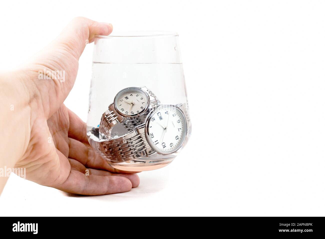 Mano uomo tenuta impermeabile, quadrante bianco, cinturino in argento, forma rotonda orologi da polso classici immersi in un vetro di acqua isolato su sfondo bianco. Foto Stock Mano uomo tenuta impermeabile, quadrante bianco, cinturino in argento, forma rotonda orologi da polso classici immersi in un vetro di acqua isolato su sfondo bianco. Foto Stock
