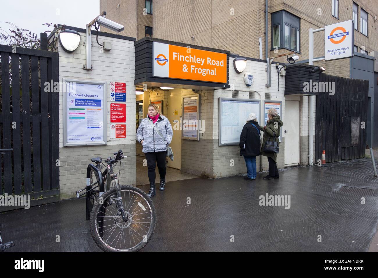 Una donna che esce dall'ingresso alla stazione ferroviaria di Finchley Road & Frognal, Londra, Regno Unito Foto Stock
