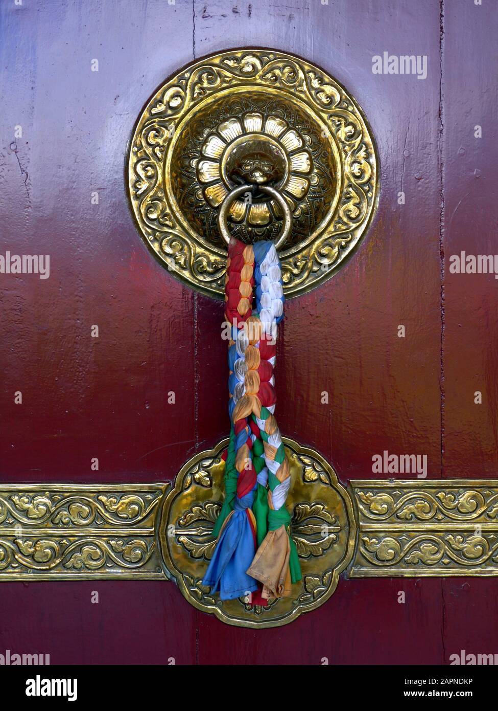 Bussare alla porta in ottone tradizionale splendidamente ornato con nastri colorati sul tempio buddista a Pokhara, Nepal Foto Stock