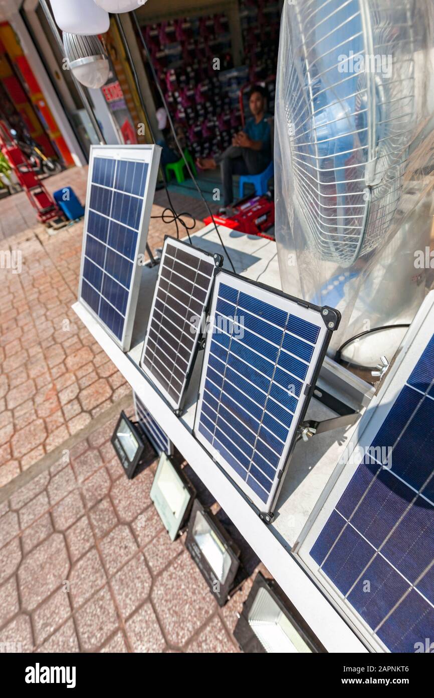 Un ventilatore elettrico e pannelli solari progettati per l'uso domestico sono due elettrodomestici in esposizione al di fuori di un negozio di elettrodomestici al dettaglio a Phnom Penh, Cambogia. Foto Stock