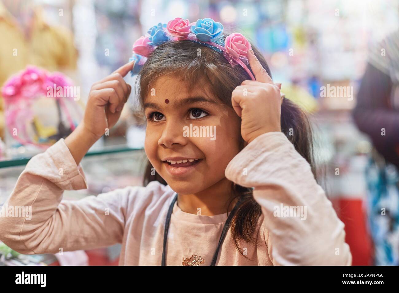 Bambina che prova su un'acconciatura con rose nel bazaar Foto Stock