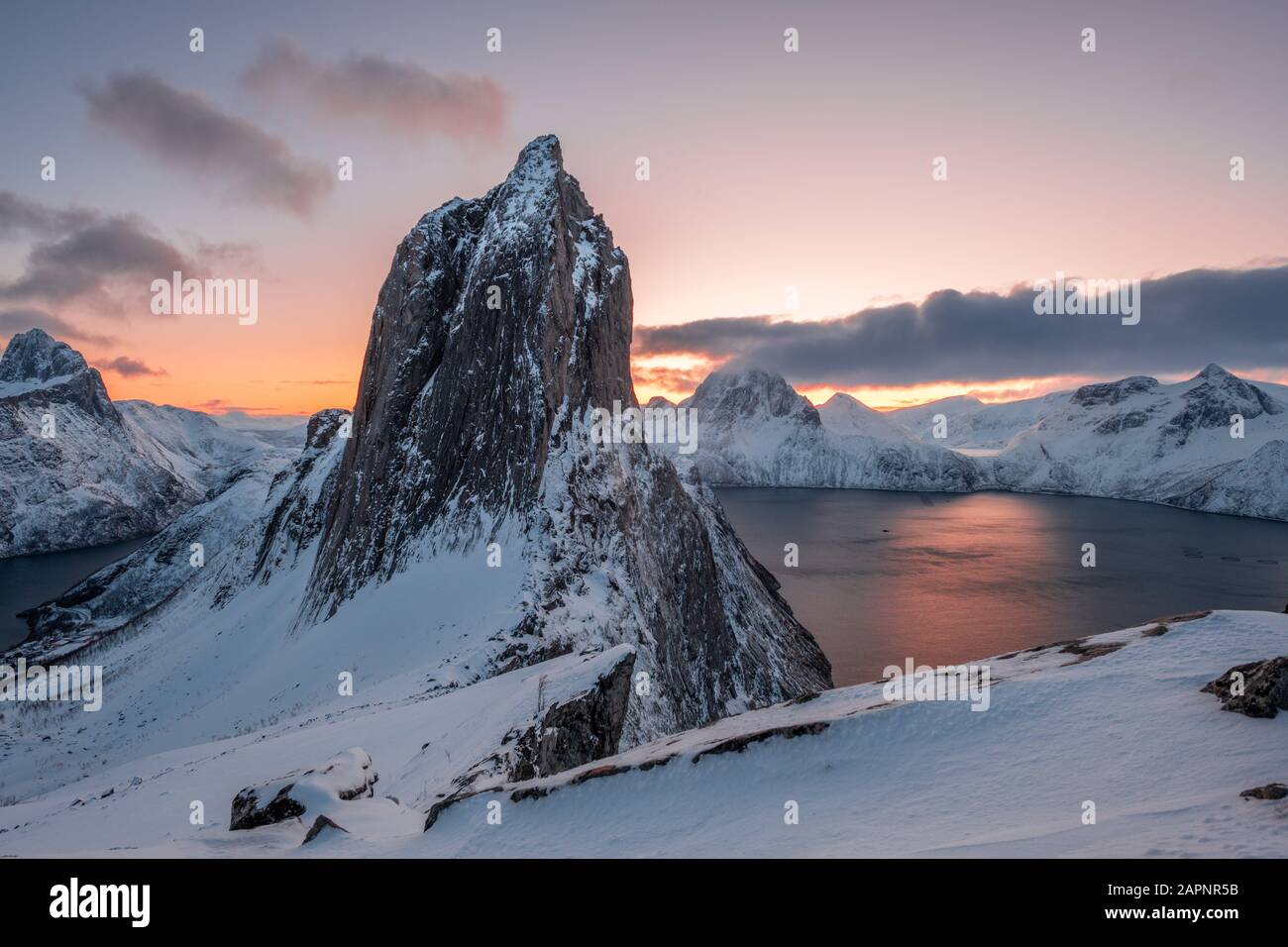 Vista dal Monte Hesten sull'Iconica montagna Segla all'alba in inverno con il cielo colorato e la catena montuosa sullo sfondo, Fjordgard, Senja, Norvegia Foto Stock