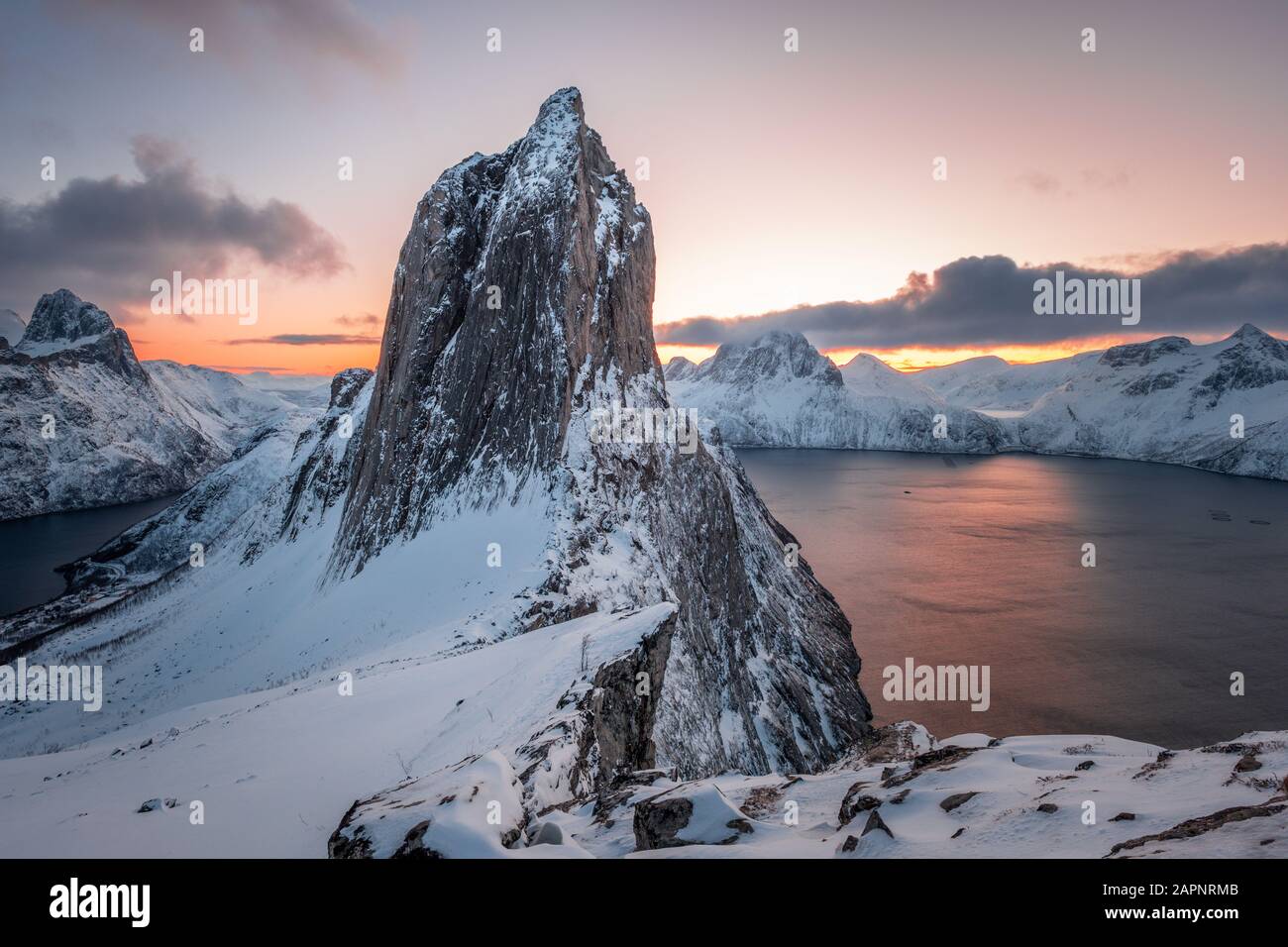 Vista dal Monte Hesten sull'Iconica montagna Segla all'alba in inverno con il cielo colorato e la catena montuosa sullo sfondo, Fjordgard, Senja, Norvegia Foto Stock