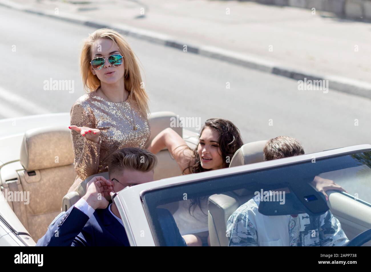 Giovani ragazze e ragazzi cavalcano in bei costumi in una cabriolet. Amici felici guidare in cabriolet auto. Auto aperta. Estate .Russia. Foto Stock