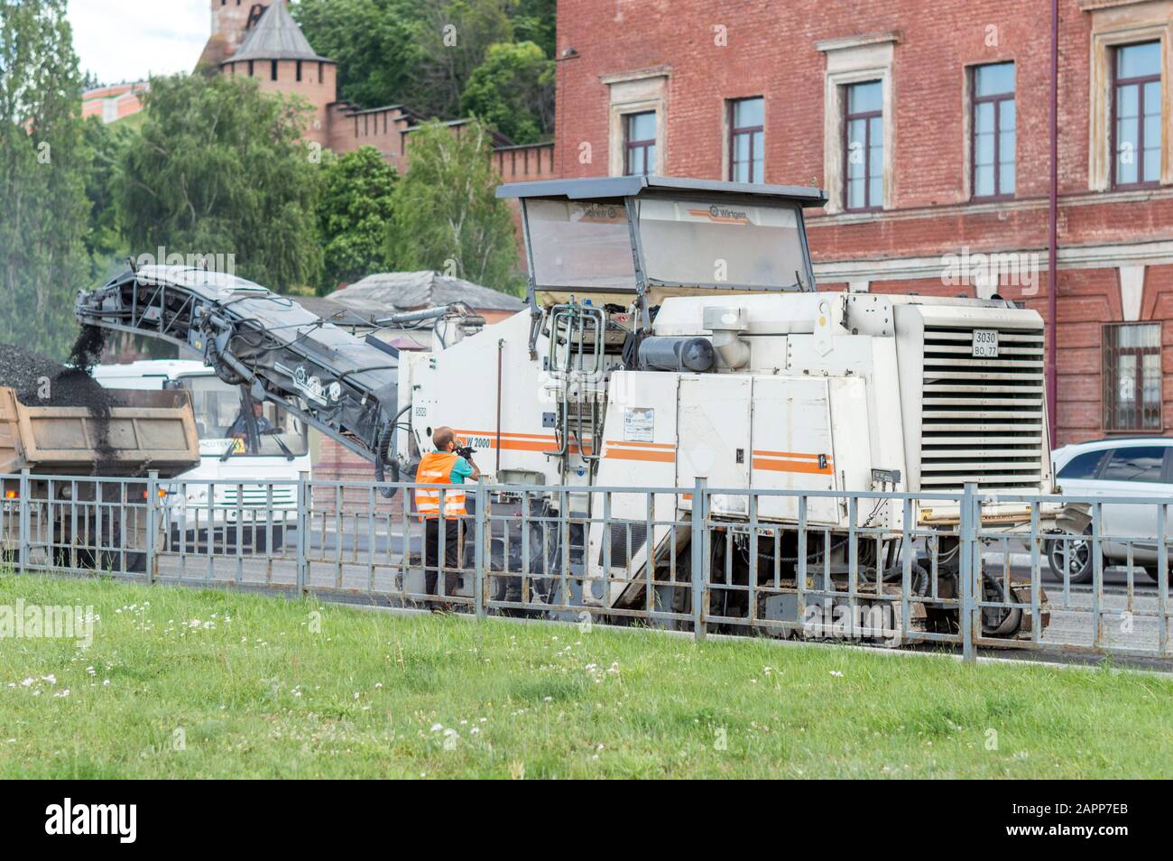 L'asfaltatrice sta lavorando al ripristino della strada. Le persone sfruttano questo meccanismo. Estate. Russia. Foto Stock