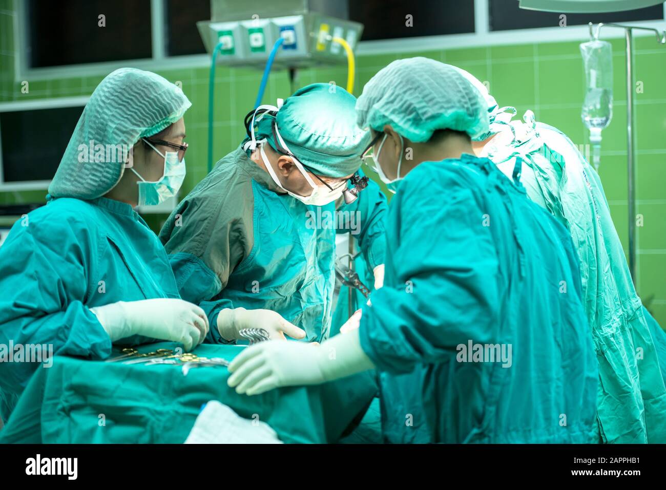 Gruppo di chirurghi al lavoro che operano in sala operatoria. Medicina di rianimazione team indossando maschere di protezione tenendo in acciaio strumenti medici salvataggio patie Foto Stock