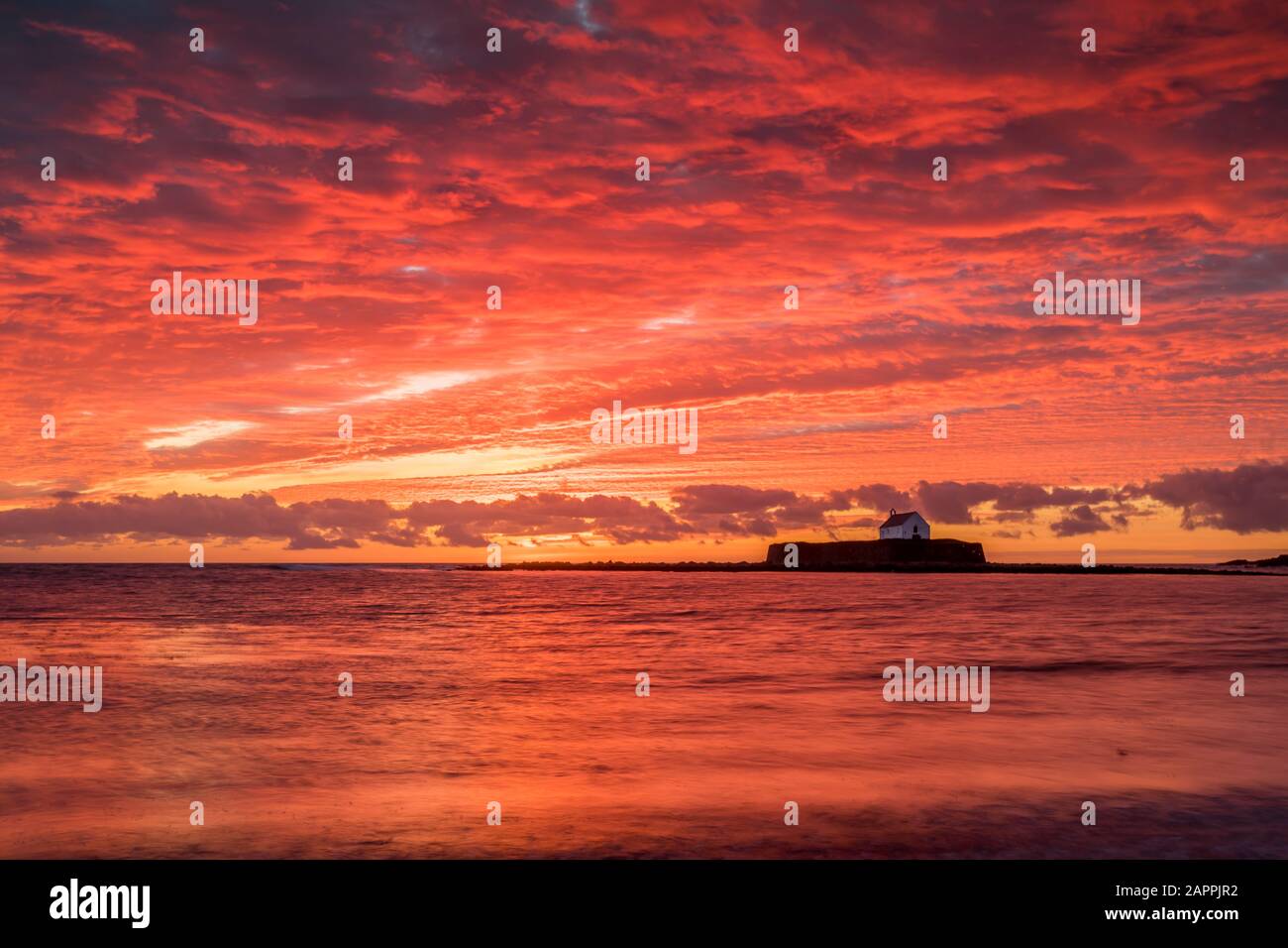 Un tramonto spettacolare alla chiesa di St Cwyfan, Anglesey, Galles Foto Stock