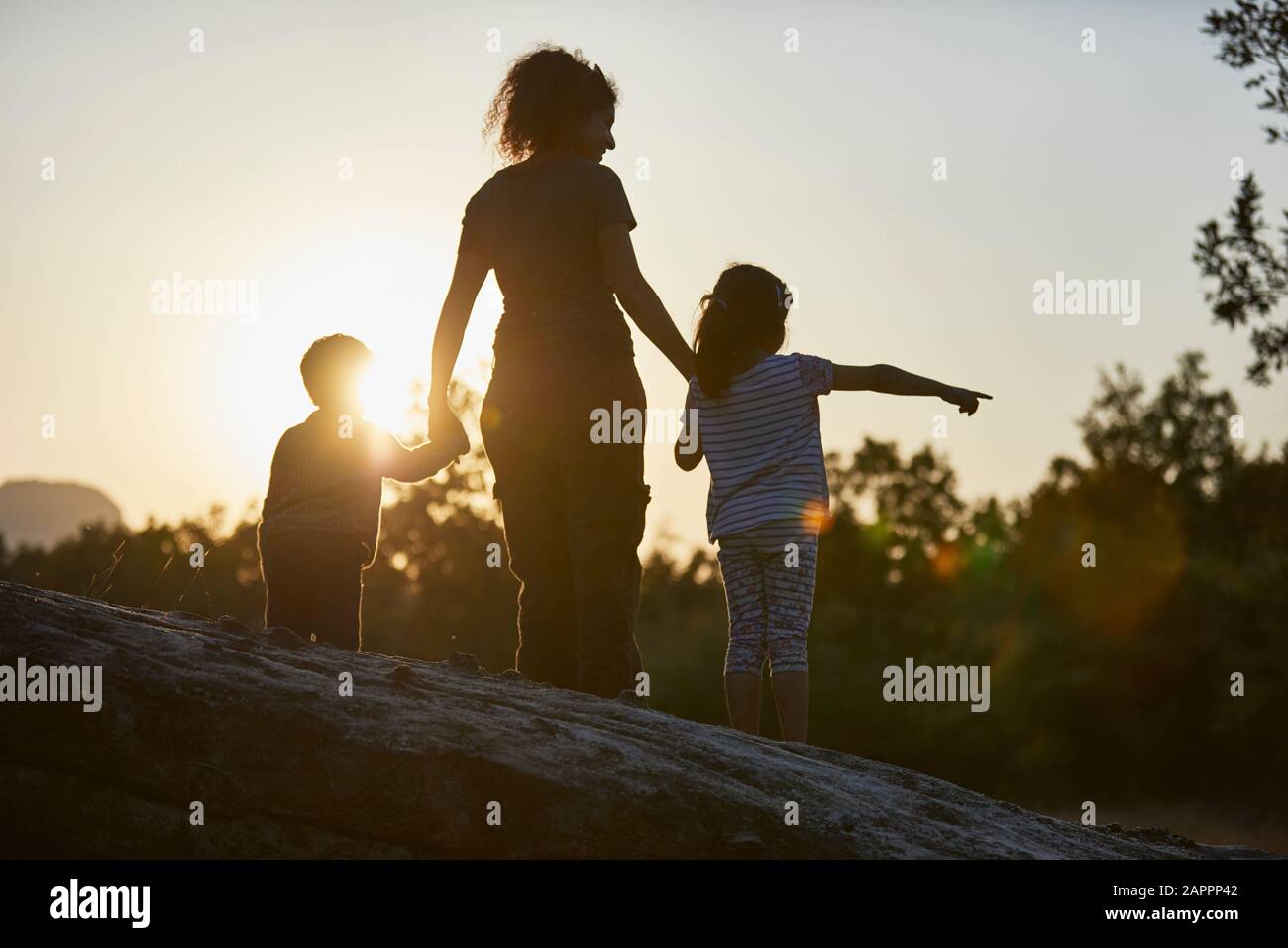 Madre e bambini che esplorano la natura al tramonto Foto Stock