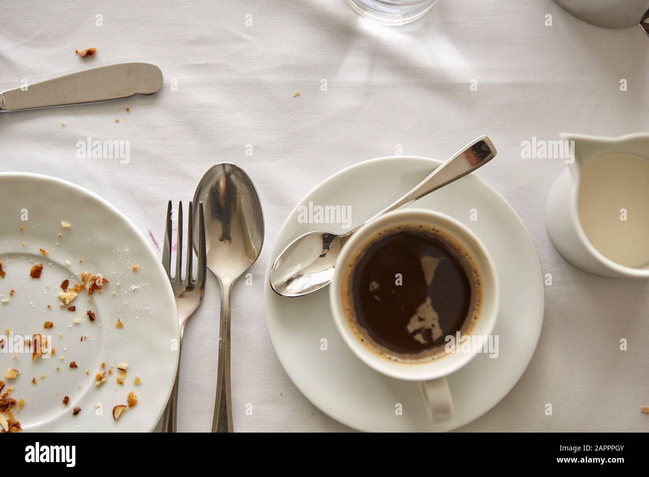 Una tazza di caffè, una tazza di latte e una piastra vuota sul tavolo Foto Stock