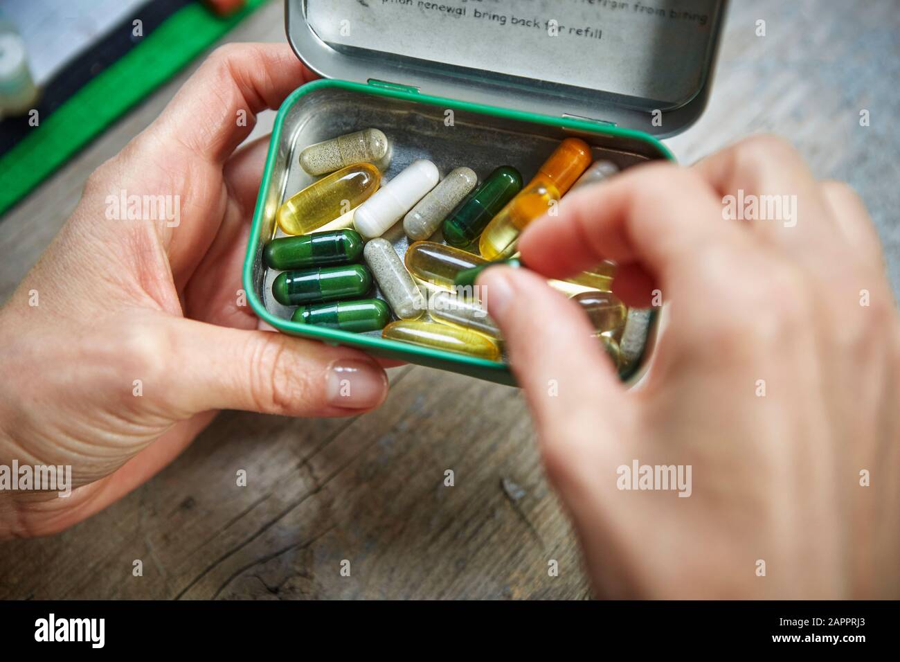 Persona che raccoglie la capsula dal pillbox tenuto in mano Foto Stock