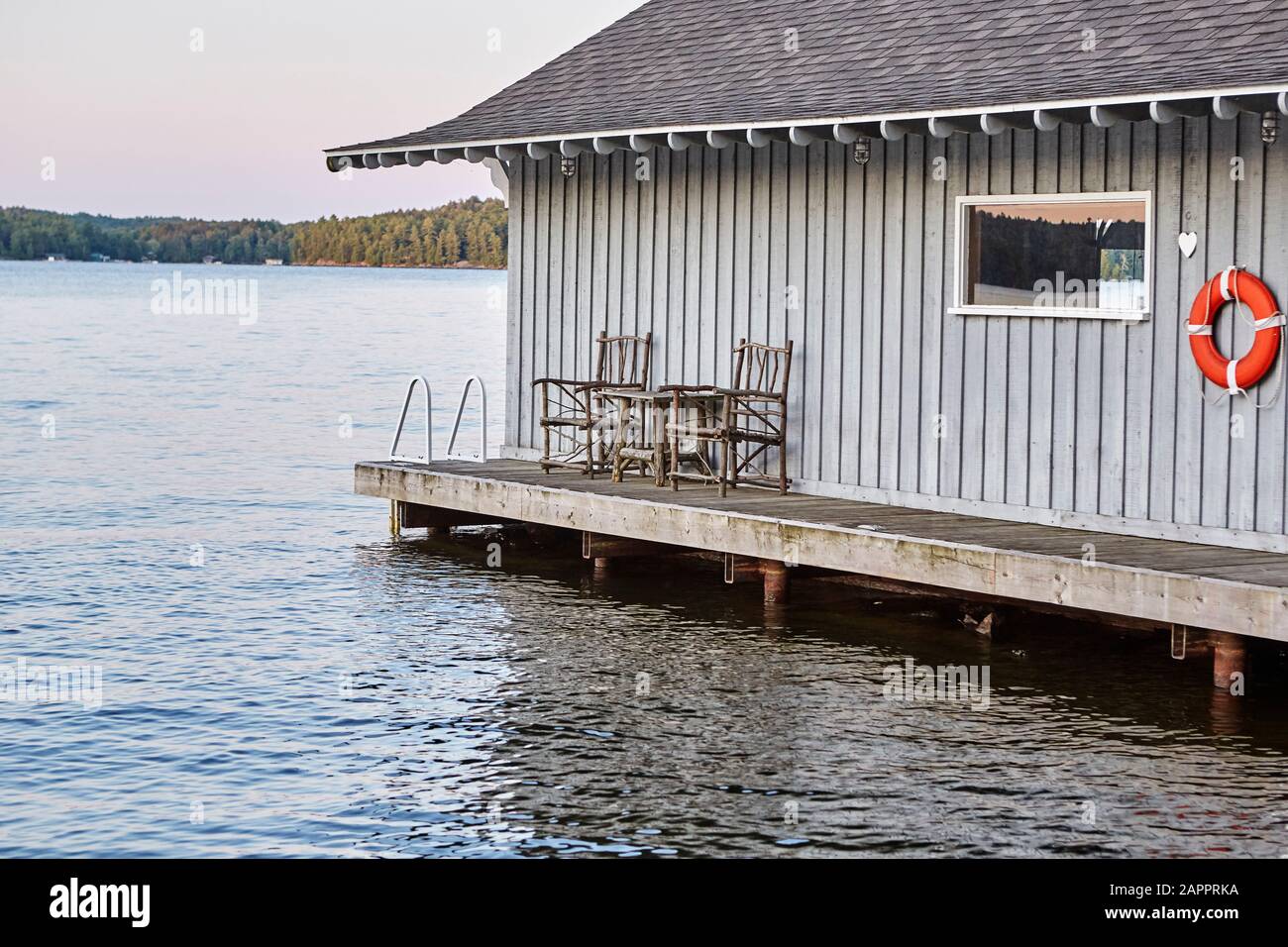 Una cabina fronte mare costruita sulle acque di un lago, sedie fatte da rami di albero in veranda Foto Stock