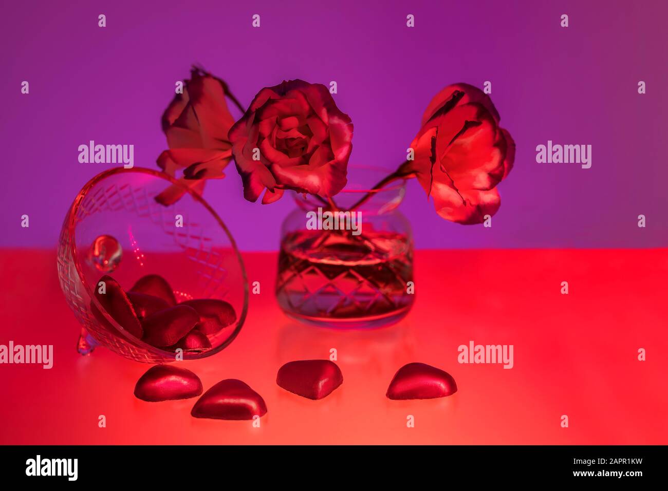 Ancora vita di fiori in vaso e cioccolatini a forma di cuore, rosso e viola. San Valentino Foto Stock