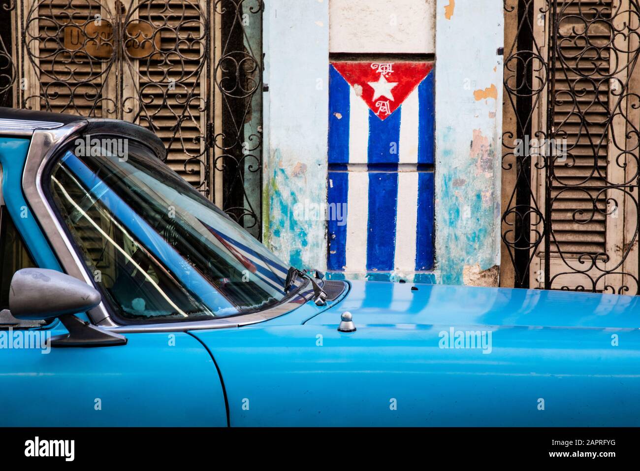 Bandiera cubana e auto blu per le strade dell'Avana; l'Avana, Cuba Foto Stock