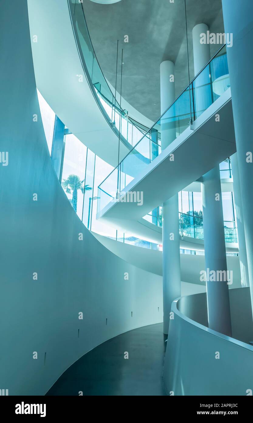 Moderna architettura interna di un corridoio con pareti bianche ricurve, colonne e vetro; Lugano, Ticino, Svizzera Foto Stock