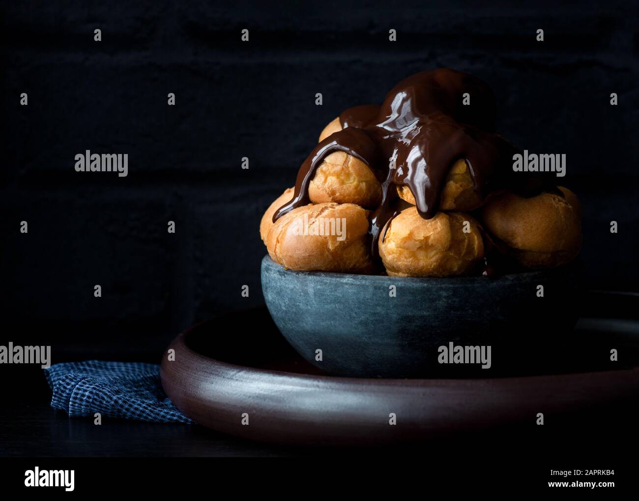 Profiteroles , pasta choux ricoperta in una salsa di cioccolato ricco di colore scuro Foto Stock