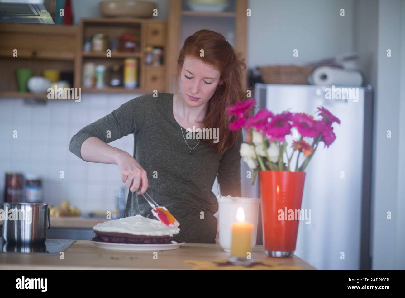 giovane donna che fa torta di compleanno a casa Foto Stock