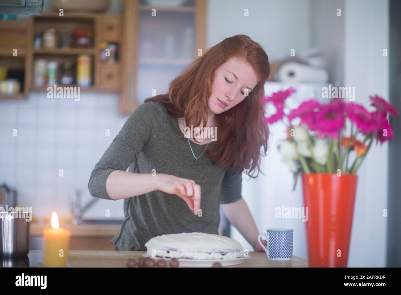 giovane donna che fa torta di compleanno a casa Foto Stock