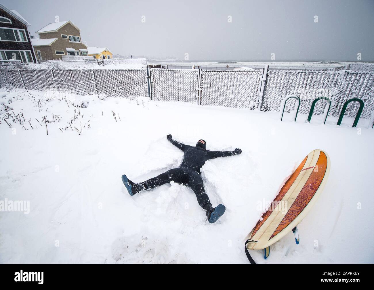 Il surfista fa l'angelo della neve nella tempesta invernale della neve del Maine Foto Stock