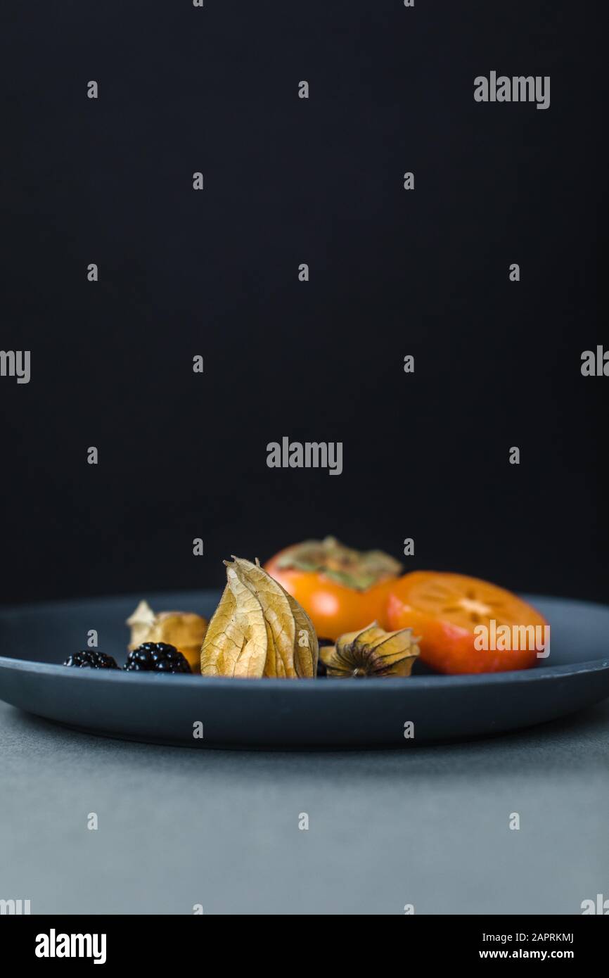 Physalis o cape gooseberries, more e kumquats su un piatto come uno spuntino sano Foto Stock