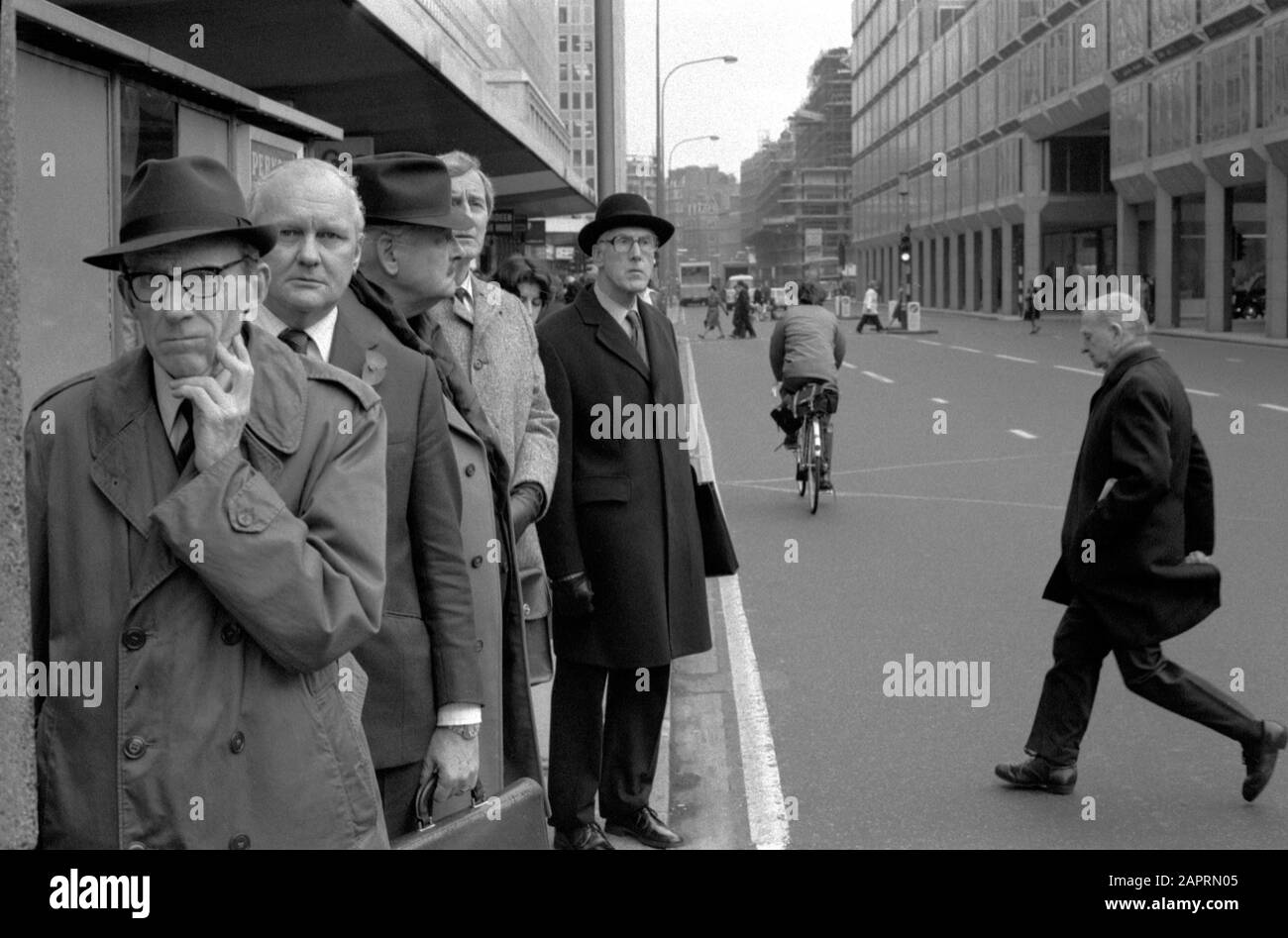 Gli impiegati pendolari si fermano alla fermata dell'autobus in attesa di un autobus. 1970s 1976 Londra UK HOMER SYKES Foto Stock